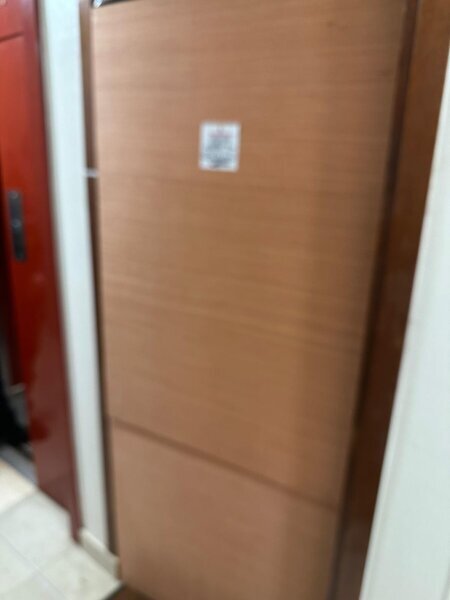 porte intérieure protégée par panneau provisoire après dépannage, chambranle blanc et porte rouge voisine