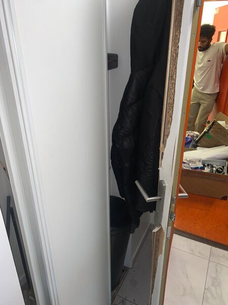 porte intérieure endommagée au niveau de la serrure avec platine métallique et poignée visible